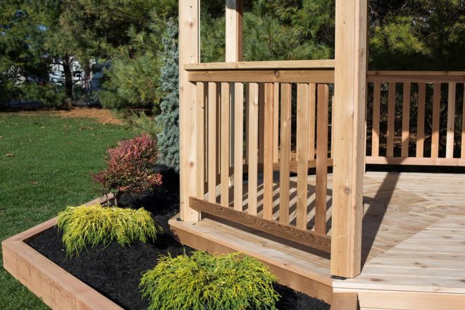 Wood gazebo handrail and a small garden row.