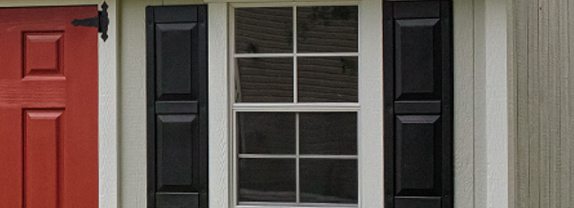 Shed window with black shutters.