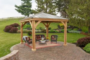 12 foot by 12 foot Wooden Pavilion Kit with a metal roof and wicker seating area.