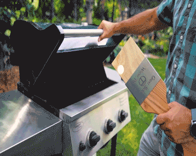 Close-up of a red brush with golden bristles and a scraper for cleaning a barbecue  grill grate. The concept of cleaning after lunch in open air, picnic,  barbecue, lunch Stock Photo by ©