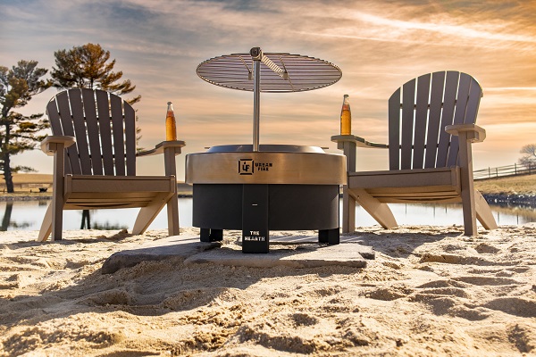 Smokeless firepit on the beach with two lawn chairs next to it.
